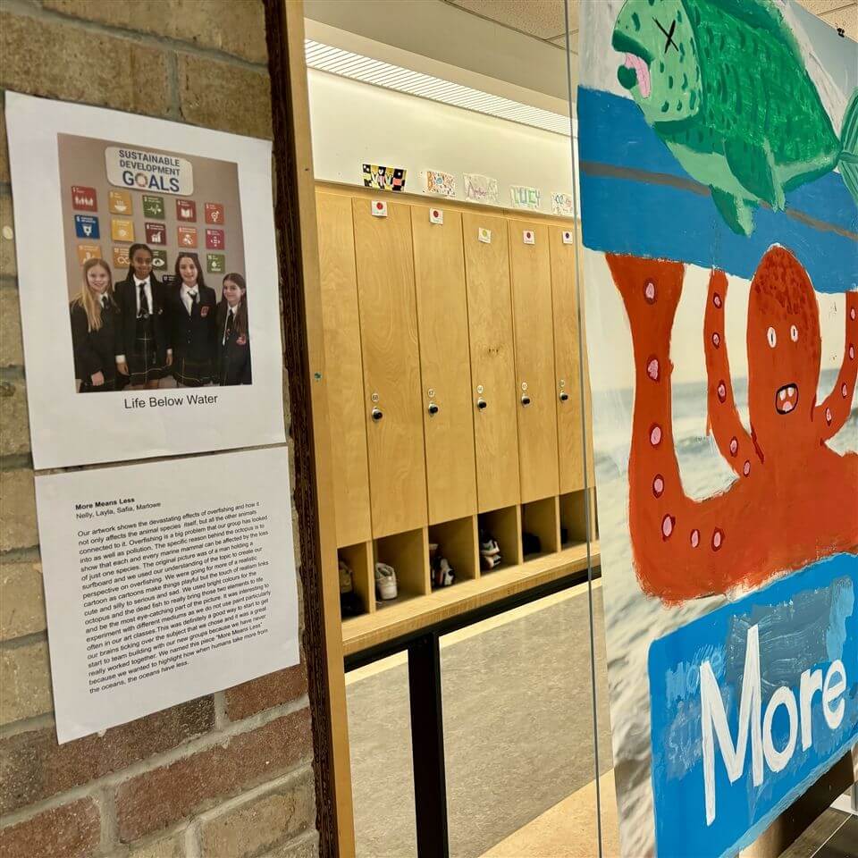 A hallway with wooden lockers, a poster about "Life Below Water" featuring four students, and a colorful painted mural of a fish and an orange octopus with the word "More.