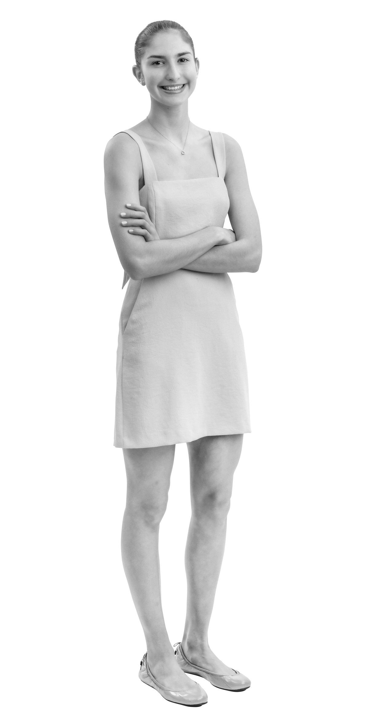 A young person with short hair stands smiling with arms crossed, wearing a sleeveless, knee-length dress and slip-on shoes. The image is in black and white with a white outline around the figure.