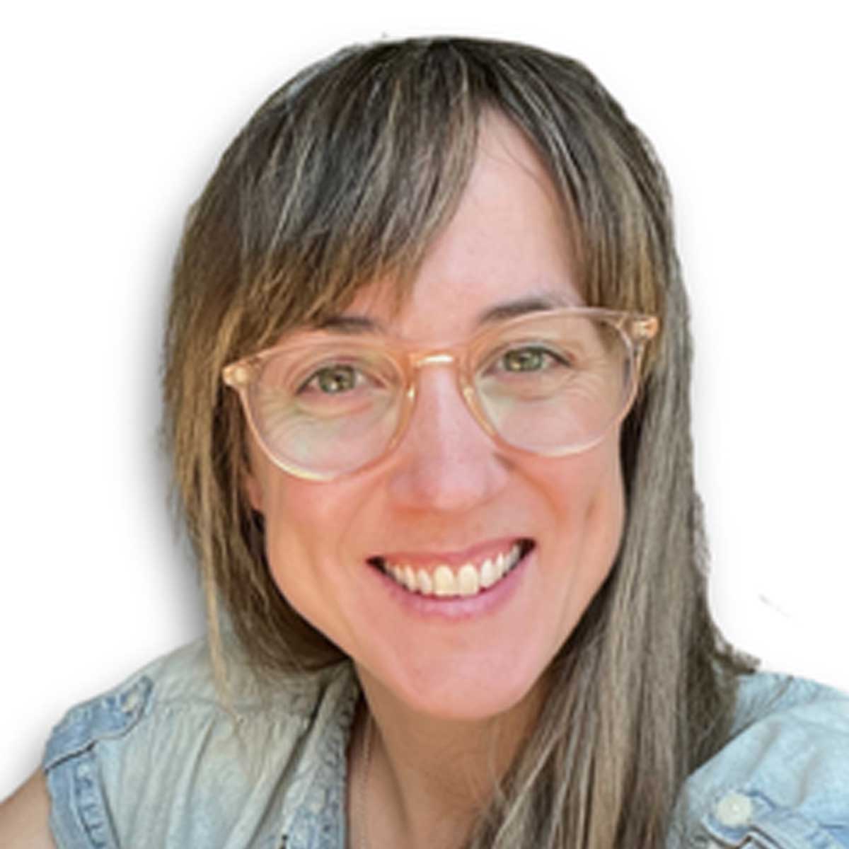 A smiling person with long brown hair, wearing clear-framed glasses and a light denim shirt, is shown against a plain white background.