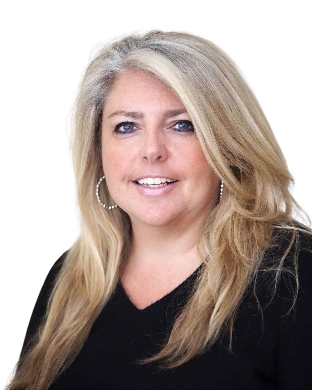 A woman with long blonde hair and hoop earrings, wearing a black top, smiles at the camera against a plain white background.