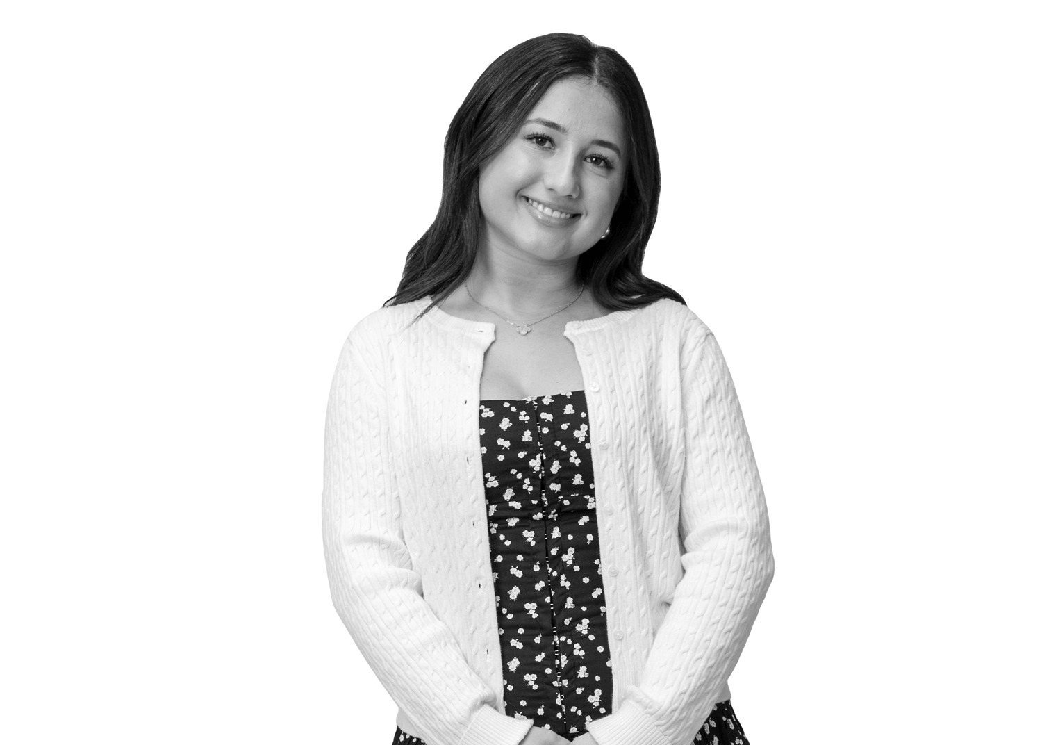 A young woman with long dark hair smiles while wearing a white cardigan over a floral dress, standing against a plain white background.