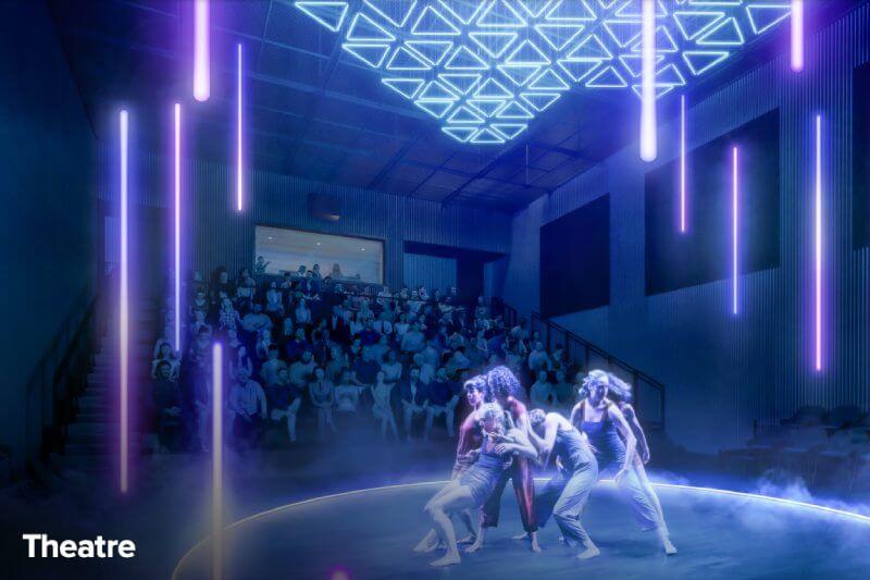 A group of dancers performs onstage under geometric blue and purple neon lights, while a seated audience watches in a modern theater. The word "Theatre" appears in the lower left corner.