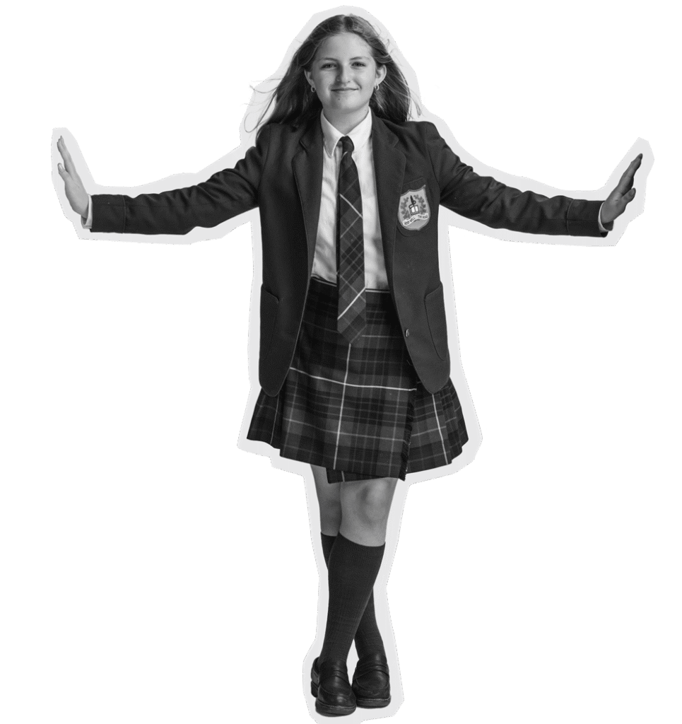 A girl in a school uniform with a plaid skirt, blazer, and tie stands with her arms outstretched, smiling. She is wearing knee-high socks and loafers. The background is plain and light-colored.