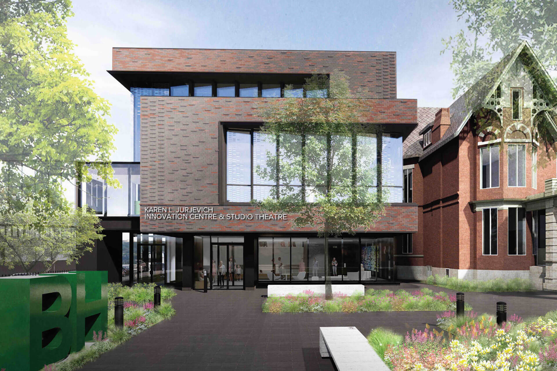 A modern brick building with large windows labeled "Karen Kain Innovation Centre & Studio Theatre," surrounded by greenery and flowers, adjacent to an older brick structure.