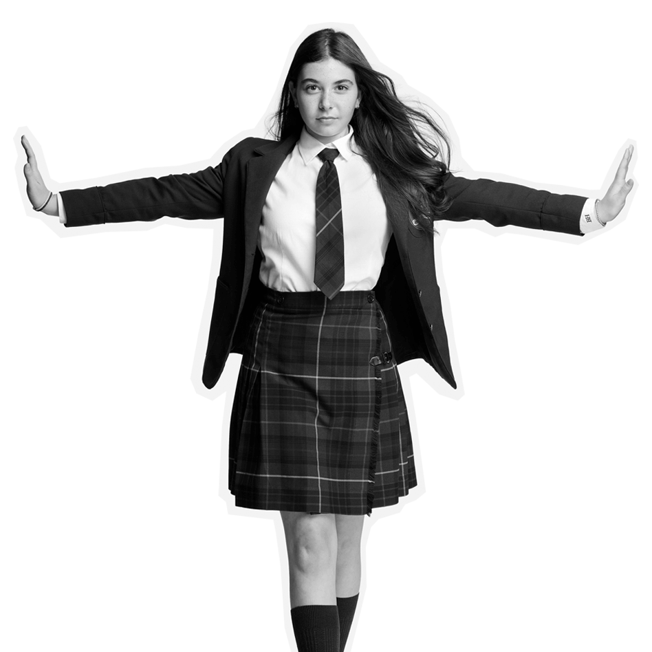 A young person in a school uniform stands with arms outstretched, palms facing forward. They wear a blazer, tie, and plaid skirt, and have long hair. The image is black and white with a cutout effect around the figure.