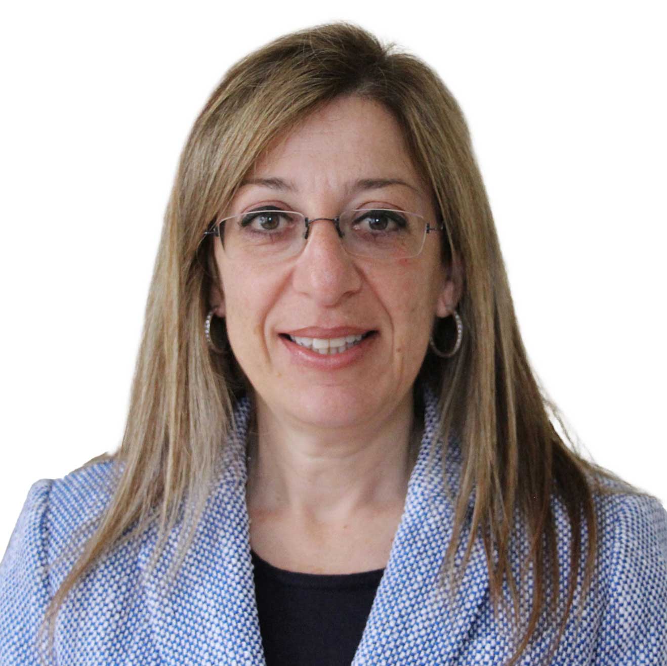 A woman with straight, light brown hair wearing glasses, hoop earrings, and a light blue textured blazer over a black top, smiling and facing the camera against a white background.