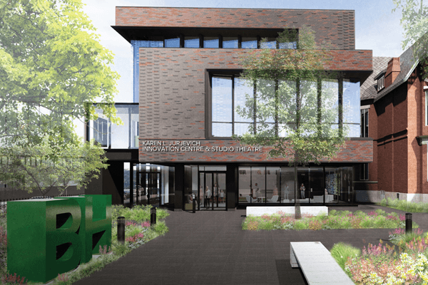 A modern building with large windows labeled "Karen LJ Jurjevich Innovation Centre & Studio Theatre," surrounded by greenery, flowers, benches, and a green sculpture featuring the letters "BH.