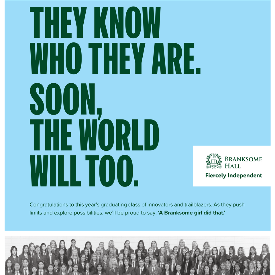 A large group of students in uniform pose for a photo beneath a blue banner reading "They know who they are. Soon, the world will too." Branksome Hall logo and message congratulating the graduating class are displayed.