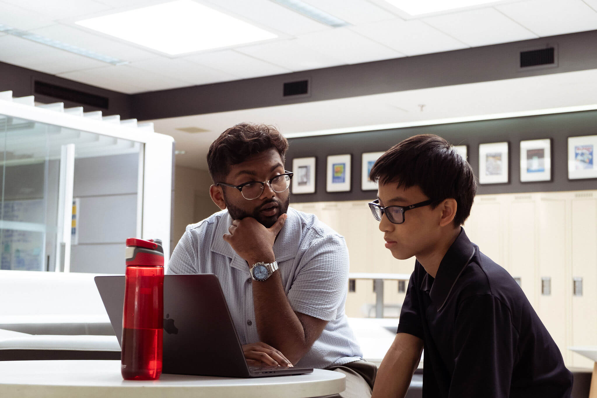 A teacher and student discuss content on the laptop